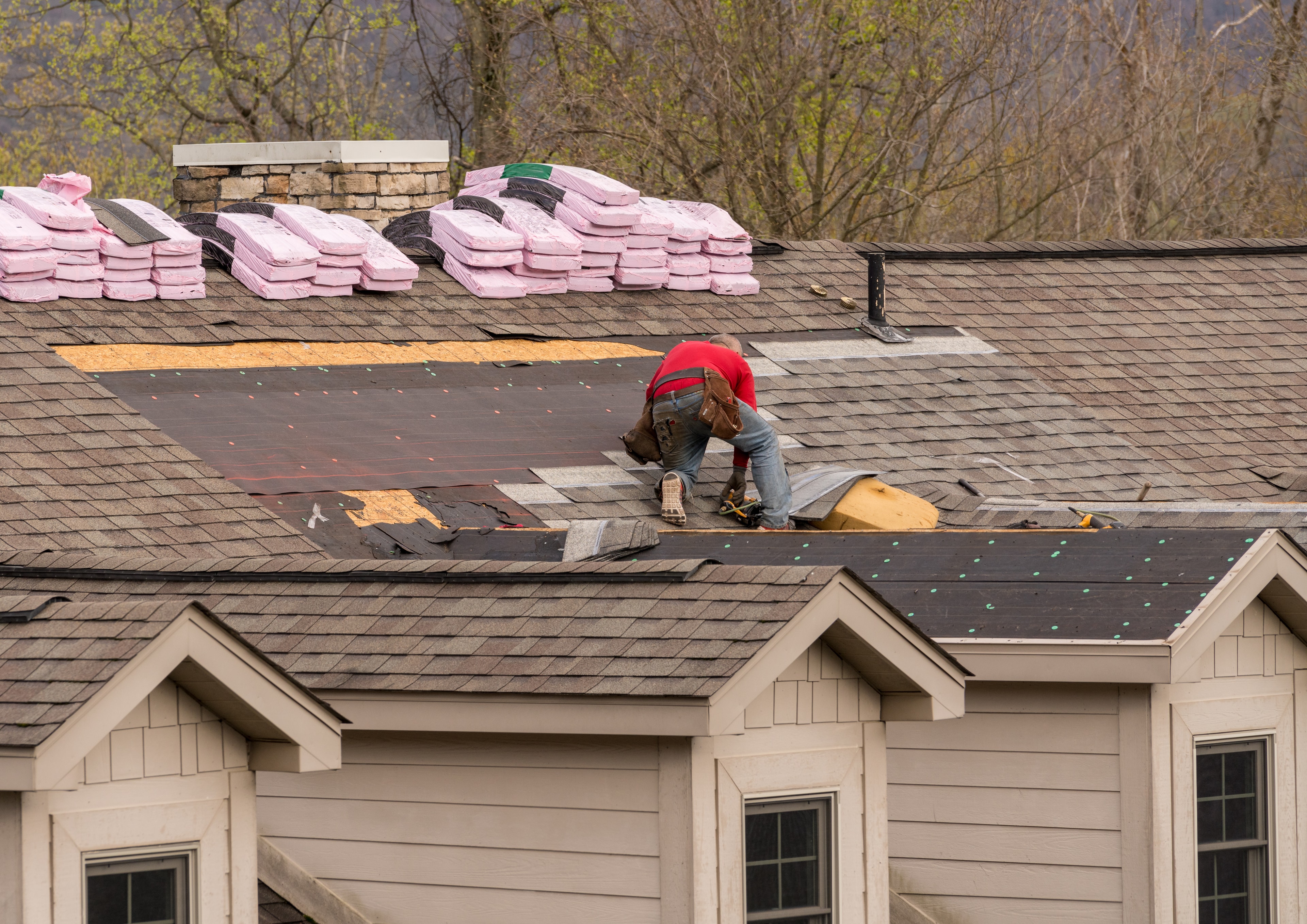 Roofer installing asphalt shingles on a house roof